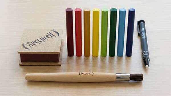 Kreisförmig angeordnete 24 Seccorell Farbstäbchen in verschiedenen Farben rund um das Seccorell-Logo in der Mitte.