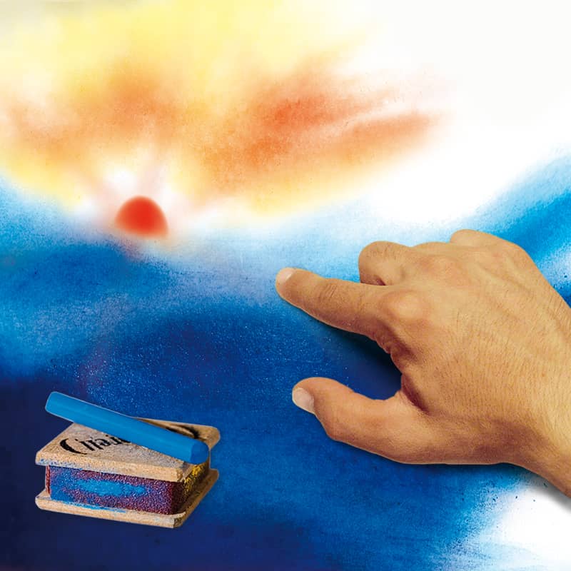 Im Vordergrund ein Seccorell-Reibeblock und Farbstäbchen. Eine Hand verwischt blaues Farbpulver. Im Hintergrund ist eine Sonne zu sehen.