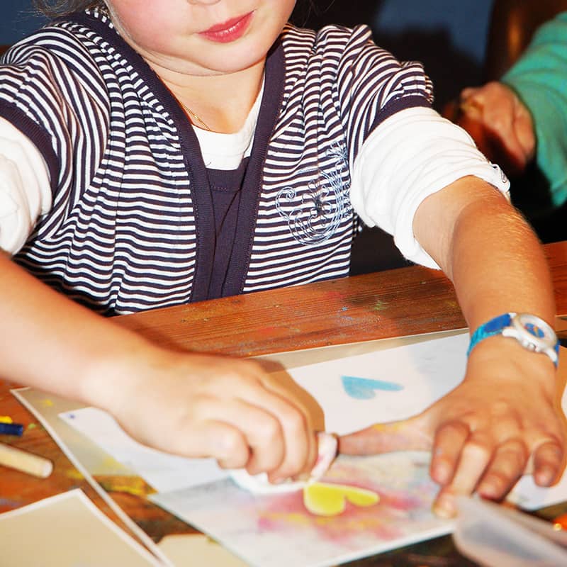 Ein Kind malt mit Seccorell ein Herz auf Papier.