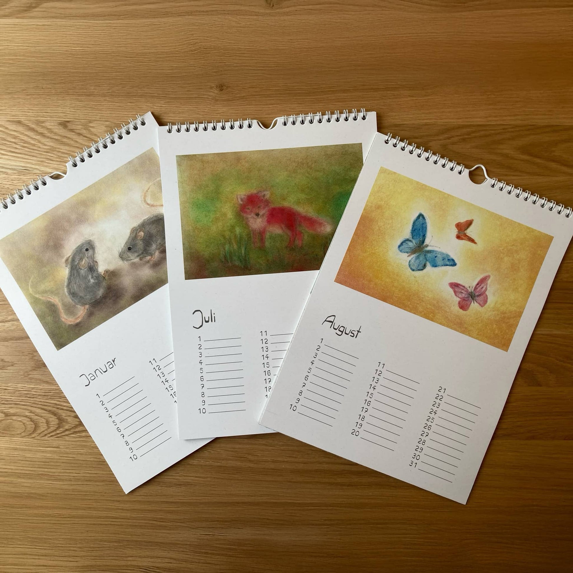 Immerwährender Tierkalender mit den Monatsseiten Januar (Mäuse), Juli (Fuchs) und August (Schmetterlinge) in Seccorell-Technik, gestaltet von Andrea Reiß.